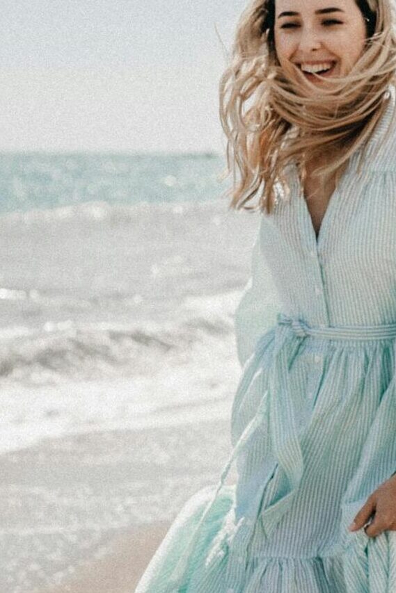 cheerful woman walking along coastline in summer sunny day A cheerful woman walking along the coastline on a sunny summer day.